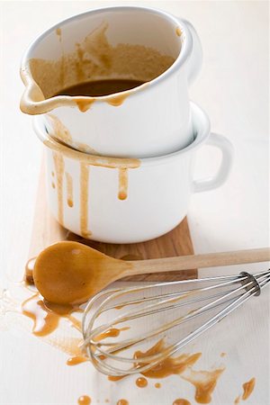 Gravy in an enamel jug, wooden spoon and whisk beside it Fotografie stock - Premium Royalty-Free, Codice: 659-01862509