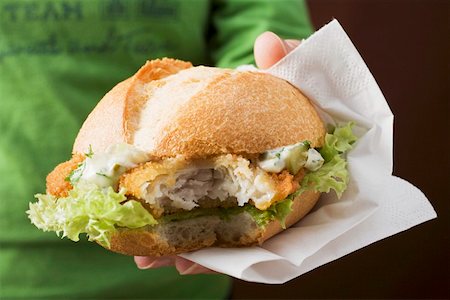 fish burger - Person holding a breaded escalope in a bread roll Stock Photo - Premium Royalty-Free, Code: 659-01862625
