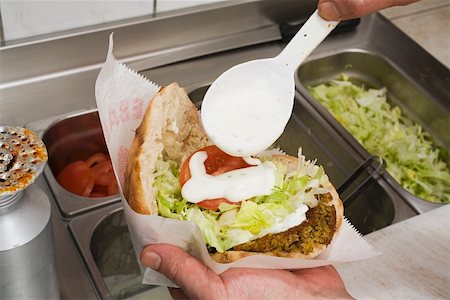 snackbar - Hinzufügen von Joghurt zu Pita-Brot gefüllt mit falafel Stockbilder - Premium RF Lizenzfrei, Bildnummer: 659-01862656