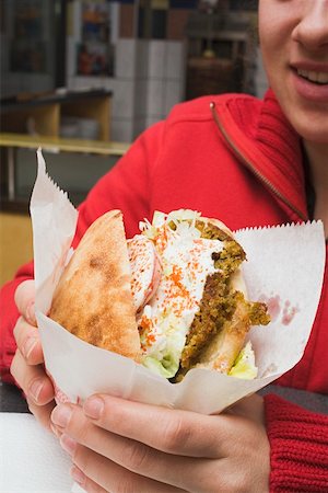 Person holding pita bread filled with falafel in snack bar Stock Photo - Premium Royalty-Free, Code: 659-01862661