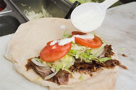 simsearch:659-01862730,k - Making a döner wrap (sprinkling with yoghurt) Foto de stock - Sin royalties Premium, Código: 659-01862671