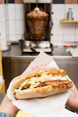 Hands holding a döner kebab in a snack bar Stock Photo - Premium Royalty-Free, Code: 659-01862728