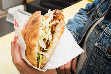 Hands holding a döner kebab in a snack bar Stock Photo - Premium Royalty-Free, Code: 659-01862729