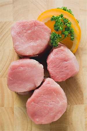 pork medallion - Four pork medallions, garnished with parsley and orange Foto de stock - Sin royalties Premium, Código: 659-01862770