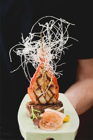 Man holding Surf & Turf (beef steak with prawn) on platter Stock Photo - Premium Royalty-Free, Code: 659-01862826