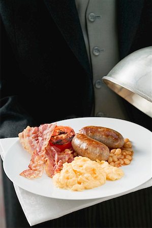 Butler serving English breakfast on plate with dome cover Stock Photo - Premium Royalty-Free, Code: 659-01862837