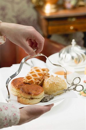 Hands serving sweet pastries and scones to eat with tea Stock Photo - Premium Royalty-Free, Code: 659-01862874