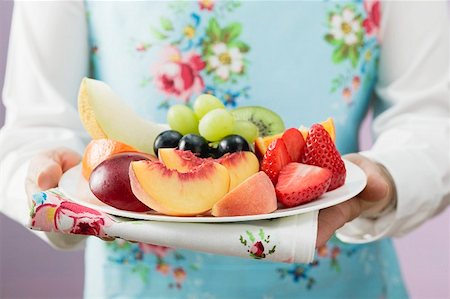 simsearch:659-01865754,k - Femme qui dessert une assiette de fruits frais Photographie de stock - Premium Libres de Droits, Code: 659-01862894
