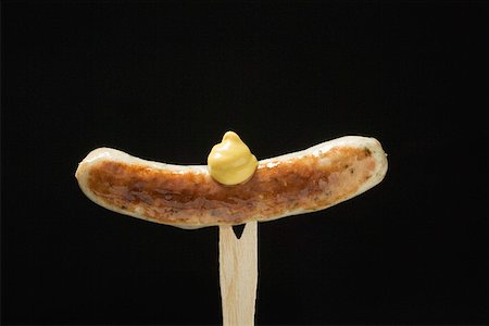 Sausage with mustard on wooden fork Stock Photo - Premium Royalty-Free, Code: 659-01863062