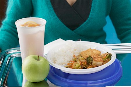 Woman holding tofu dish, apple and drink on tray Stock Photo - Premium Royalty-Free, Code: 659-01863084