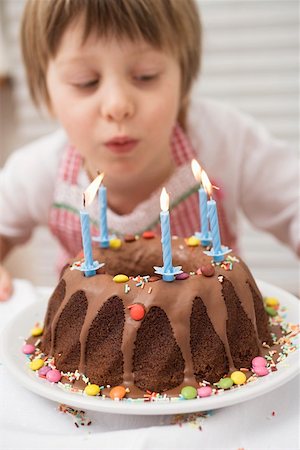 soplar velas - Small boy blowing out candles on birthday cake Foto de stock - Sin royalties Premium, Código: 659-01863098
