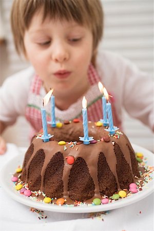 ring cake - Small boy blowing out candles on birthday cake Stock Photo - Premium Royalty-Free, Code: 659-01863098