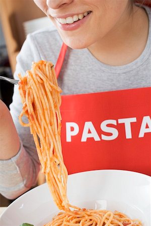 simsearch:659-01855701,k - Young woman in apron eating spaghetti with tomato sauce Stock Photo - Premium Royalty-Free, Code: 659-01863197