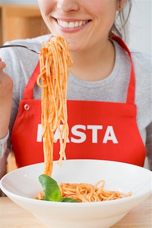 simsearch:659-01855701,k - Young woman in apron eating spaghetti with tomato sauce Stock Photo - Premium Royalty-Free, Code: 659-01863198