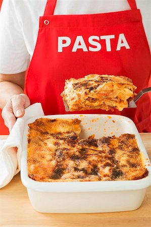 Woman taking portion of lasagne out of baking dish Stock Photo - Premium Royalty-Free, Code: 659-01863214