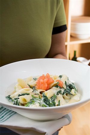 spinach pasta - Woman holding plate of penne with spinach and tomatoes Stock Photo - Premium Royalty-Free, Code: 659-01863267