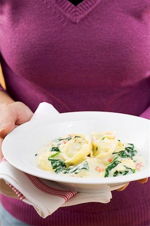 spinach pasta - Woman holding plate of tortellini with spinach & cream sauce Stock Photo - Premium Royalty-Free, Code: 659-01863260