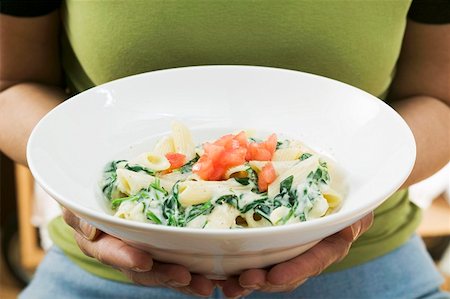 spinach pasta - Woman holding plate of penne with spinach and tomatoes Stock Photo - Premium Royalty-Free, Code: 659-01863261