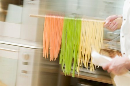 simsearch:659-01852572,k - Chef hurrying through kitchen with ribbon pasta on wooden spoon Stock Photo - Premium Royalty-Free, Code: 659-01863290