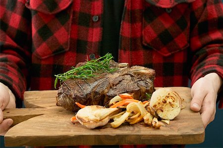 simsearch:659-01862823,k - Man serving grilled T-bone steak on chopping board Foto de stock - Sin royalties Premium, Código: 659-01863428