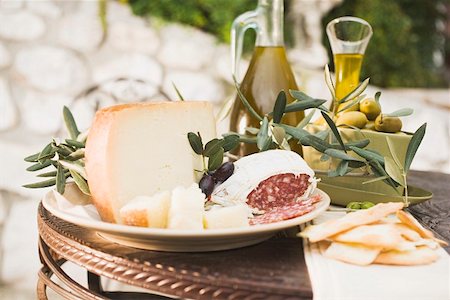 Fromage, salami, olives, huile d'olive craquelins sur table en plein air Photographie de stock - Premium Libres de Droits, Code: 659-01863596