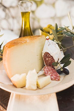 Cheese, salami, olives and olive oil on table out of doors Stock Photo - Premium Royalty-Free, Code: 659-01863593