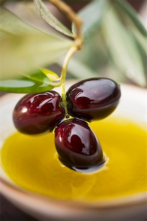 Dipping olive sprig with black olives in olive oil Fotografie stock - Premium Royalty-Free, Codice: 659-01863620