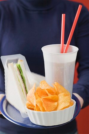 Woman holding sandwich, cola and crisps on tray Stock Photo - Premium Royalty-Free, Code: 659-01863789