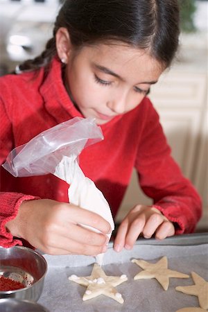 Girl icing biscuits with piping bag Stock Photo - Premium Royalty-Free, Code: 659-02214201