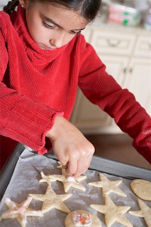 Girl decorating biscuits with coloured sugar sprinkles Stock Photo - Premium Royalty-Free, Code: 659-02214202