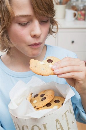 simsearch:659-03522828,k - Boy eating chocolate chip cookie out of cookie tin Stock Photo - Premium Royalty-Free, Code: 659-02214339