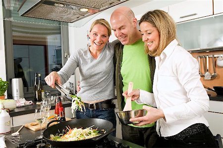 Man and two women cooking a stir- fry together Foto de stock - Sin royalties Premium, Código: 659-02210840