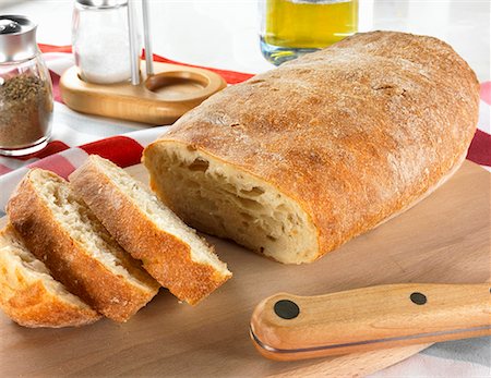 sliced white bread - Ciabatta on wooden board, pepper, salt & olive oil behind Stock Photo - Premium Royalty-Free, Code: 659-02211143