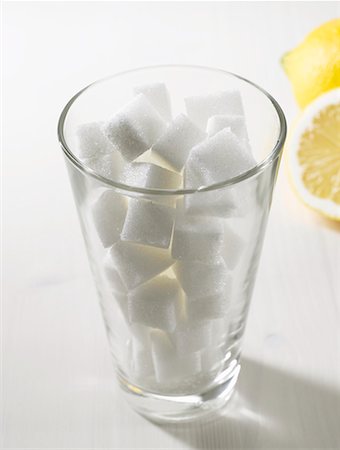 Sugar cubes in tumbler, lemons in background Foto de stock - Royalty Free Premium, Número: 659-02211349