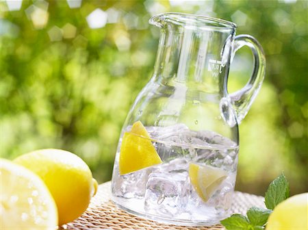 summer drink - Verseuse en verre d'eau minérale avec des quartiers de citron et de cubes de glace Photographie de stock - Premium Libres de Droits, Code: 659-02211417