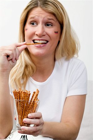 simsearch:659-02211464,k - Jeune femme avec des couleurs allemandes sur son visage manger bâtonnets salés Photographie de stock - Premium Libres de Droits, Code: 659-02211487