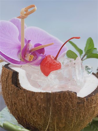 Half a coconut with ice cubes, cocktail cherry and orchid Stock Photo - Premium Royalty-Free, Code: 659-02211703
