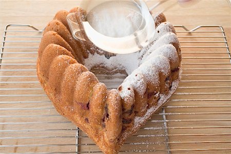 dredging sugar - Sprinkling heart-shaped ring cake with icing sugar Stock Photo - Premium Royalty-Free, Code: 659-02211723