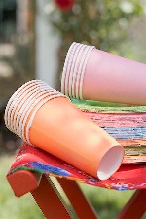 Papier de couleur tasses et assiettes sur tabouret pliant dans le jardin Photographie de stock - Premium Libres de Droits, Code: 659-02211763