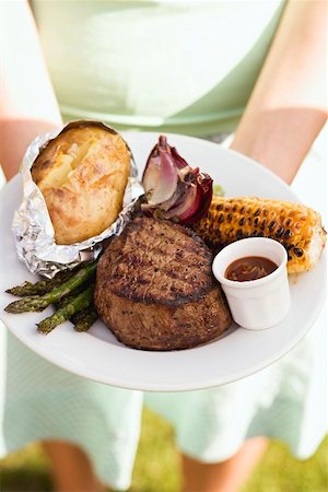 simsearch:659-01863429,k - Woman holding a plate of grilled steak and accompaniments Stock Photo - Premium Royalty-Free, Code: 659-02211817