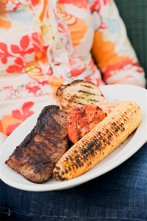 simsearch:659-01863429,k - Woman holding a plate of grilled steak and accompaniments Stock Photo - Premium Royalty-Free, Code: 659-02211822