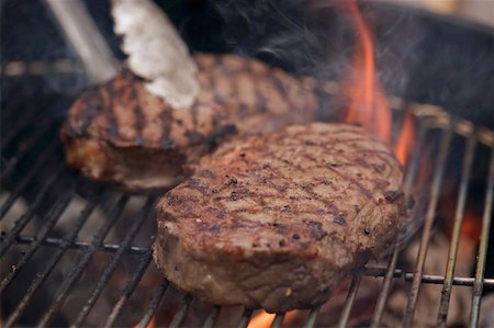 Beef steaks on a barbecue with barbecue tongs Stock Photo - Premium Royalty-Free, Code: 659-02211952