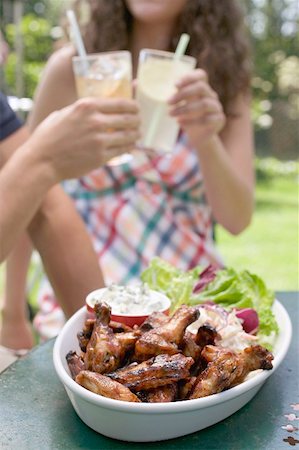 simsearch:659-03524301,k - Grilled chicken wings with salad, young people in background Fotografie stock - Premium Royalty-Free, Codice: 659-02211965