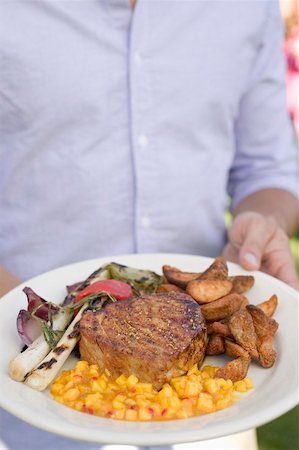 simsearch:659-02211984,k - Man holding plate of grilled steak and accompaniments Fotografie stock - Premium Royalty-Free, Codice: 659-02211968