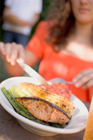 simsearch:659-02211982,k - Woman eating grilled salmon with corn on the cob & vegetables Stock Photo - Premium Royalty-Free, Code: 659-02212006