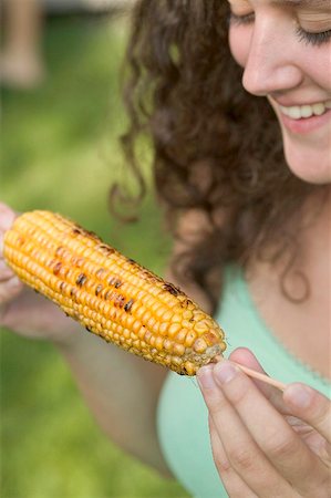 Woman holding grilled corn on the cob Stock Photo - Premium Royalty-Free, Code: 659-02212054