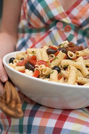 Woman holding large dish of pasta salad with olives & tomatoes Fotografie stock - Premium Royalty-Free, Codice: 659-02212082