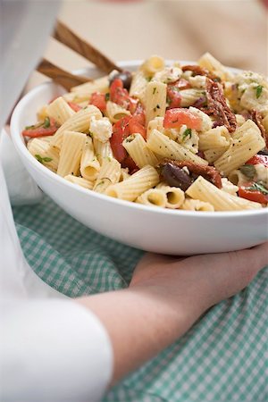 Woman holding dish of pasta salad with olives and tomatoes Fotografie stock - Premium Royalty-Free, Codice: 659-02212083
