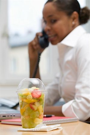 fruitsalad takeaway - Salade de fruits dans un contenant en plastique, la femme au téléphone en arrière-plan Photographie de stock - Premium Libres de Droits, Code: 659-02212385