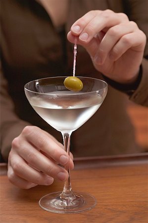 simsearch:659-06155164,k - Woman holding olive on cocktail stick over glass of Martini Foto de stock - Sin royalties Premium, Código: 659-02212394